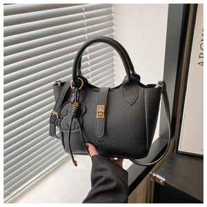 Détail du sac seau noir en cuir grainé avec charm ours mignon et finitions dorées