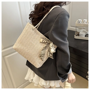 Detail of a beige woven tote bag with a silk scarf handle and a chevron texture pattern