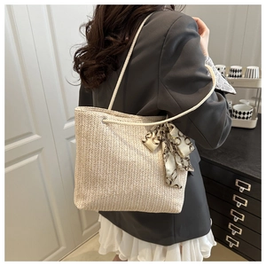 Detail of straw tote bag with V-shaped weave, white rope handles and silk scarf accent
