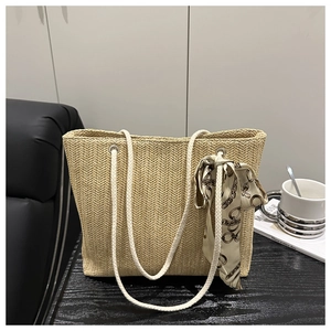Detail of woven straw tote bag with rope handles and decorative printed silk scarf