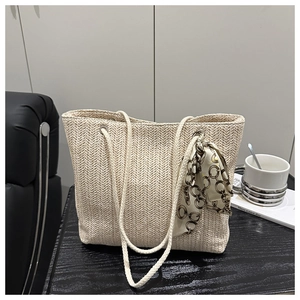 Detailed texture of straw woven tote bag with cotton rope handles and silk scarf detail
