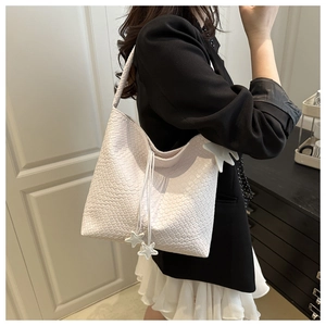 Détail du sac cabas tressé crème avec pendentifs étoiles et bandoulière épaisse