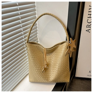 Vue détaillée d'un sac cabas tressé champagne avec breloque étoile et détails de cordon