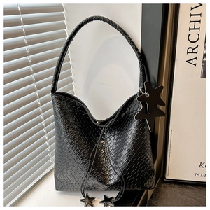 Détail du sac hobo en cuir tressé noir avec breloques étoiles et poignée tressée élégante