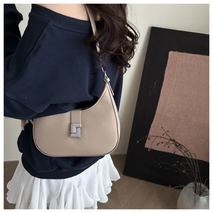 Chic beige crescent shoulder bag with silver metallic clasp shown on model