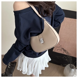 Detailed view of beige crescent shoulder bag with silver clasp on casual outfit