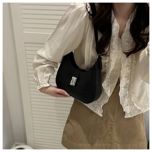 Close-up of black half-moon underarm bag with silver square metal buckle and smooth leather texture