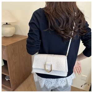 White woven crossbody bag with gold hardware shown on model in home setting