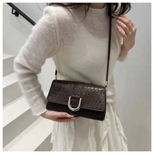 Detailed shot of dark brown faux leather bag with crocodile texture and gold U-buckle