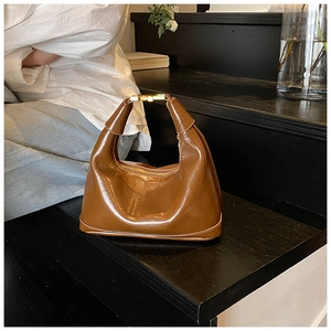 Detailed macro view of the glossy brown leather bag texture with gold metal buckle