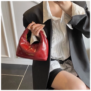 Détail du sac rouge en cuir verni avec finitions dorées et lettrage décoratif fashion
