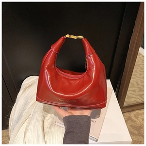 Detail of red glossy leather hobo bag with gold hardware and Fashion & Bags text