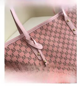 Macro detail of pink tote bag showing leather handles and golden metal M logo pendant