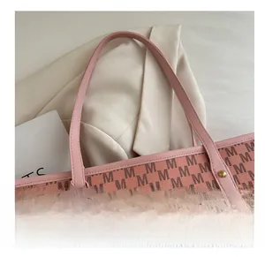 Detailed view of pink tote bag with M-letter print and gold rivet reinforcement