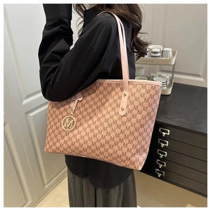 Macro detail of pink tote bag with M-pattern texture and golden M-letter pendant