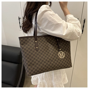 Détail du cabas marron avec motif monogramme M et pendentif doré en gros plan