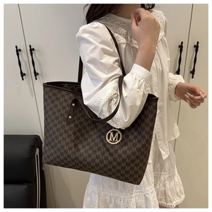 Detail of dark brown tote bag with monogram print and golden M letter charm pendant