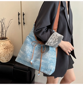 Detail of denim tote bag with brown leather straps, bow tie, and beaded tassel accents