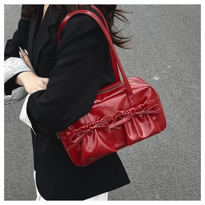 Detail of red patent leather tote bag with stylish bows and pleated design