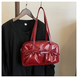 Close-up of a red shiny patent leather underarm bag with bow-knot pleated pockets