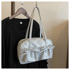 Detail of white glossy shoulder bag featuring double pockets and 3D bow accents