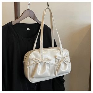 Detail of creamy white glossy shoulder bag featuring drawstring pockets and chic bows
