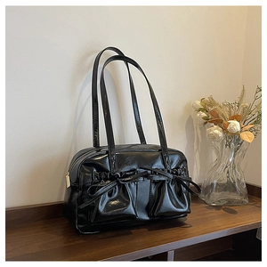 Detail of black glossy shoulder bag with pleated texture and decorative ribbon pockets