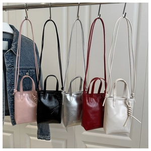 Close-up of five colored mini tote bags hanging in pink, silver, red, black, and white