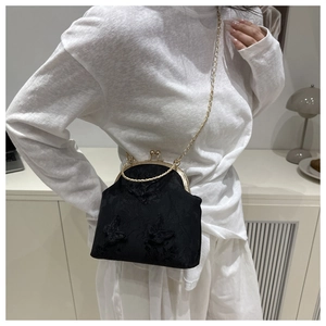 Detalle de bolso de encaje negro con bordado de mariposa y cadena de metal dorada