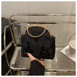 Detail of black vintage kiss-lock bag with butterfly embroidery and gold chain strap