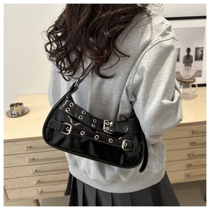 Détail du sac à bandoulière en cuir verni noir avec boucles et œillets argentés