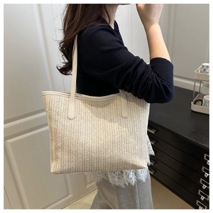 Détail du sac cabas tressé crème avec texture à chevrons et anses en cuir élégantes