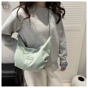 Close-up of light green crescent tote bag with textured fabric and FANYISSA label