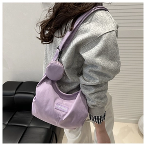Detail view of purple corduroy tote bag with small round coin purse on shoulder strap