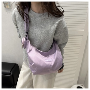 Close-up of lavender nylon crescent bag with small round coin purse and brand logo tag