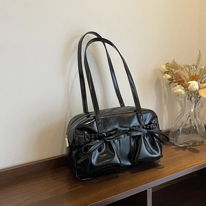 Glossy black underarm bag with decorative bow pockets and slim shoulder straps