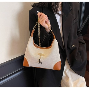 Close-up of minimalist tote bag with canvas fabric, brown leather trim and gold chain