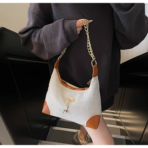 Detail of canvas tote bag featuring leather trim, gold chain, and cute deer charm
