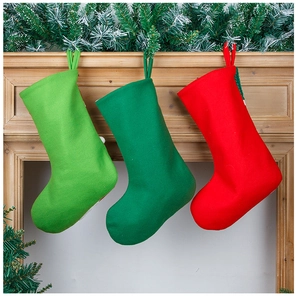 Three embroidered Christmas stockings in red and green hanging on a rustic wooden mantel