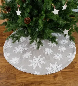 Detail der grauen Plüsch-Weihnachtsbaumdecke mit weißen 3D-Schneeflocken auf Holzboden