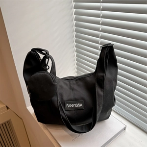 Black canvas tote bag with wide strap and mini coin pouch on minimalist background