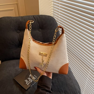 Minimalist canvas and brown leather tote bag with gold hardware and chain strap
