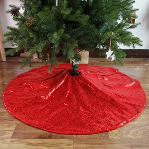 Sparkling red sequin Christmas tree skirt with festive holiday decor on wooden floor