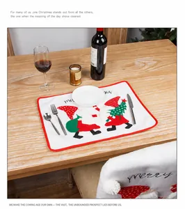 Close-up of white Christmas placemat with red borders and festive embroidery on wood table
