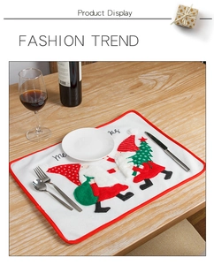 Detail of Christmas table mat with embroidered gnomes and Merry text on wooden table