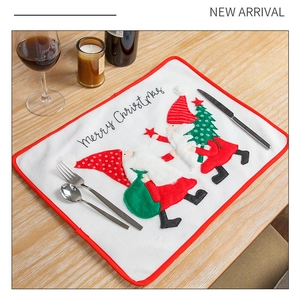 Detail of Christmas table mat with embroidered gnome design on wooden background