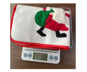 Détail du set de table de Noël blanc brodé posé sur une balance électronique