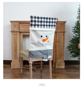 Détail d'une housse de chaise bonhomme de neige avec carreaux rouge et blanc près du sapin