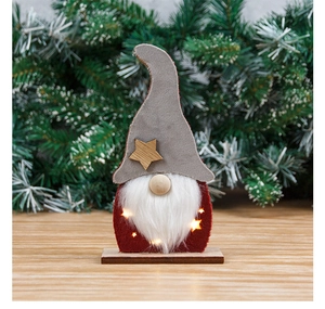 Close-up of a lit Christmas gnome ornament with LED star lights on a wooden base
