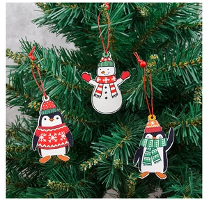 Detailed view of wooden snowman and penguin ornaments hanging on a Christmas tree